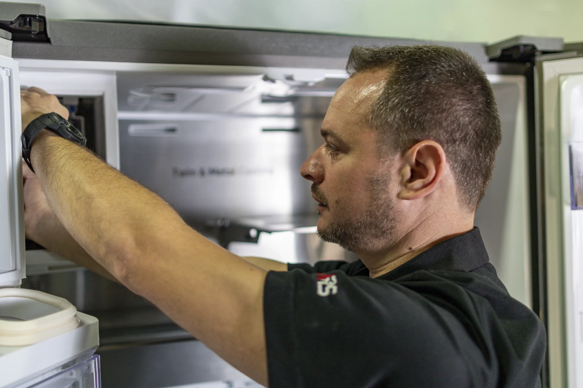 Technician examining refrigerator cooling and water system Technician examining refrigerator cooling and water system
