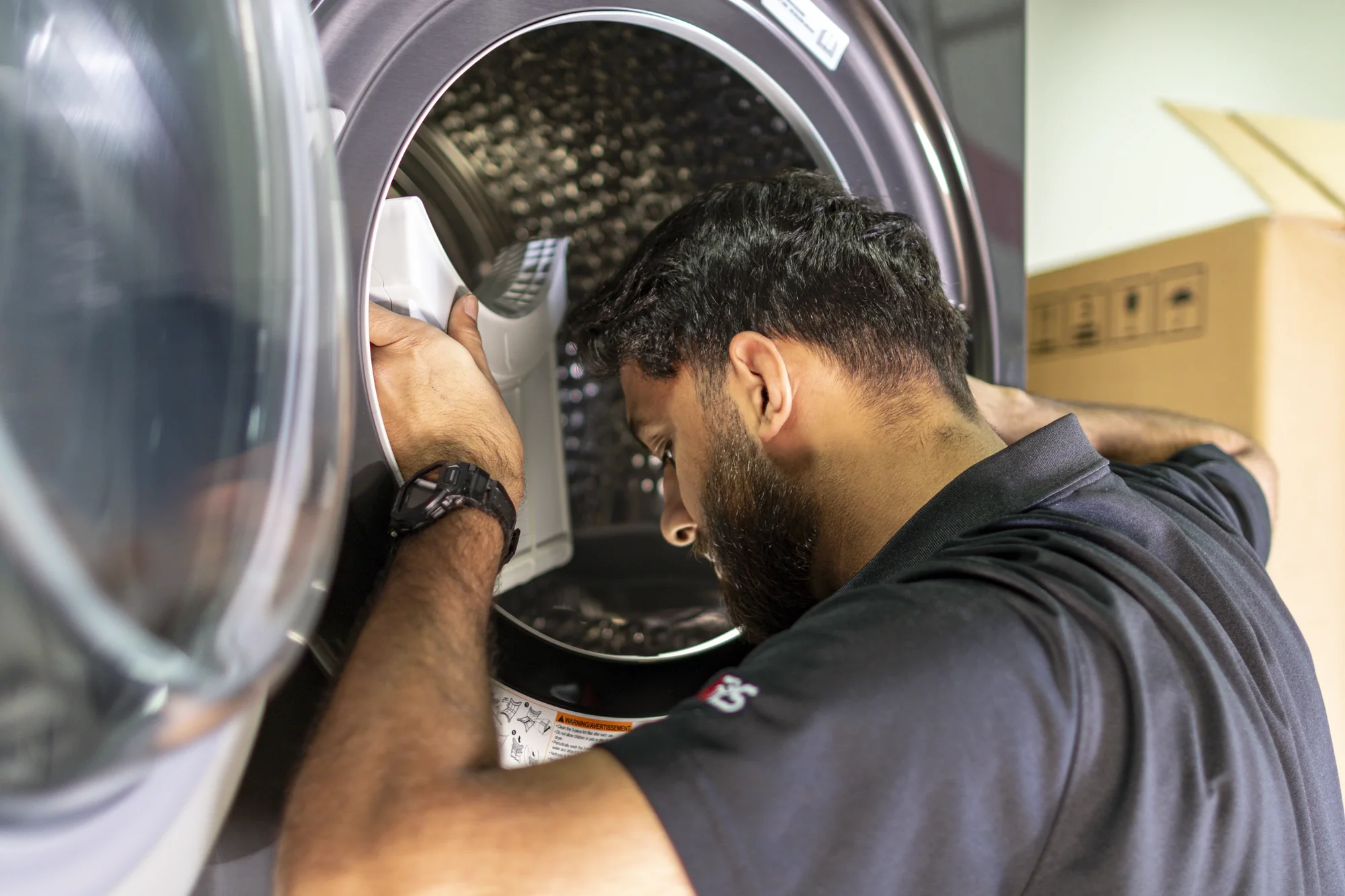 Technician inspecting and cleaning a front-load dryer Technician inspecting and cleaning a front-load dryer
