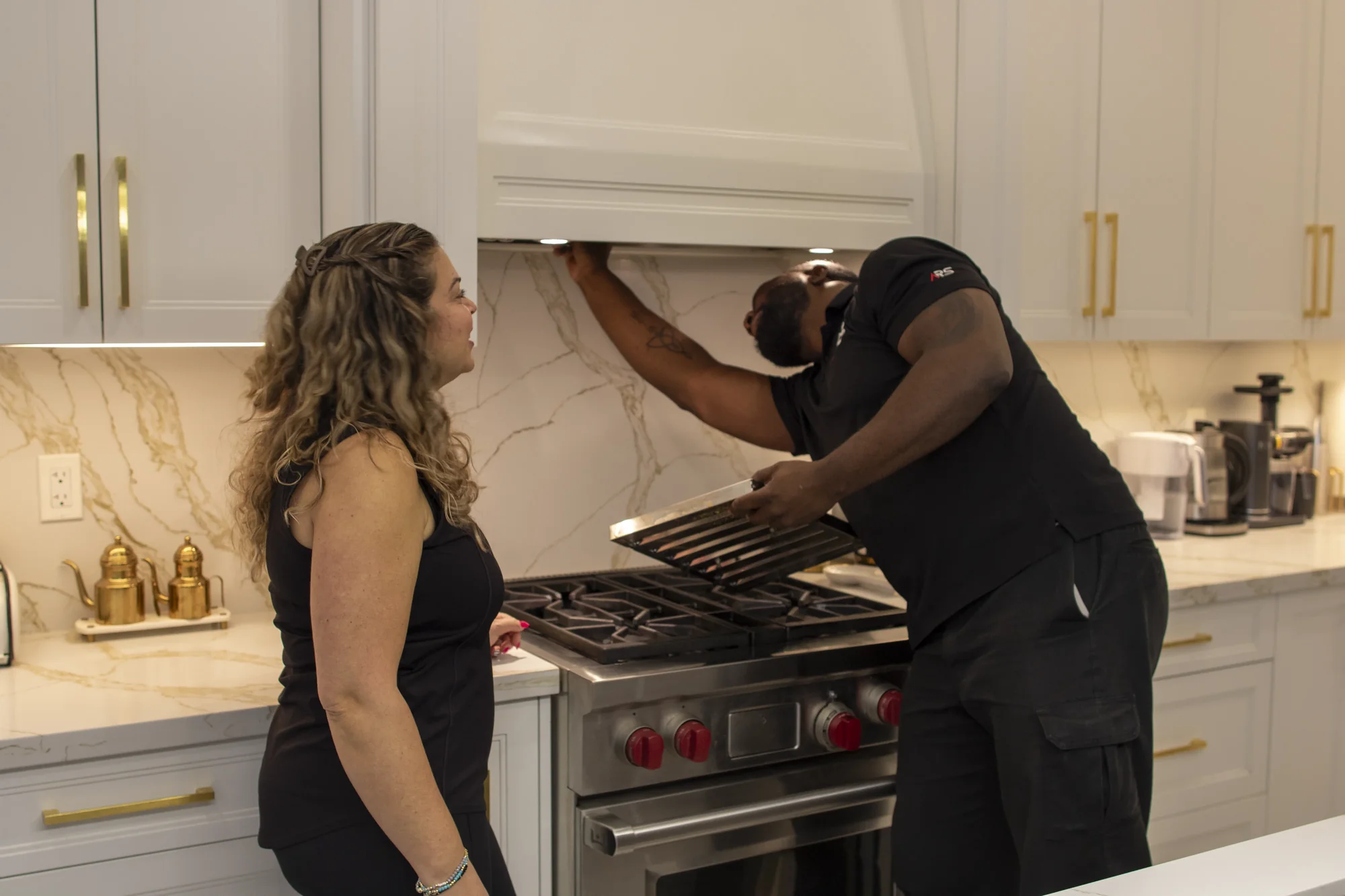Technician inspecting range hood motor and controls Technician inspecting range hood motor and controls